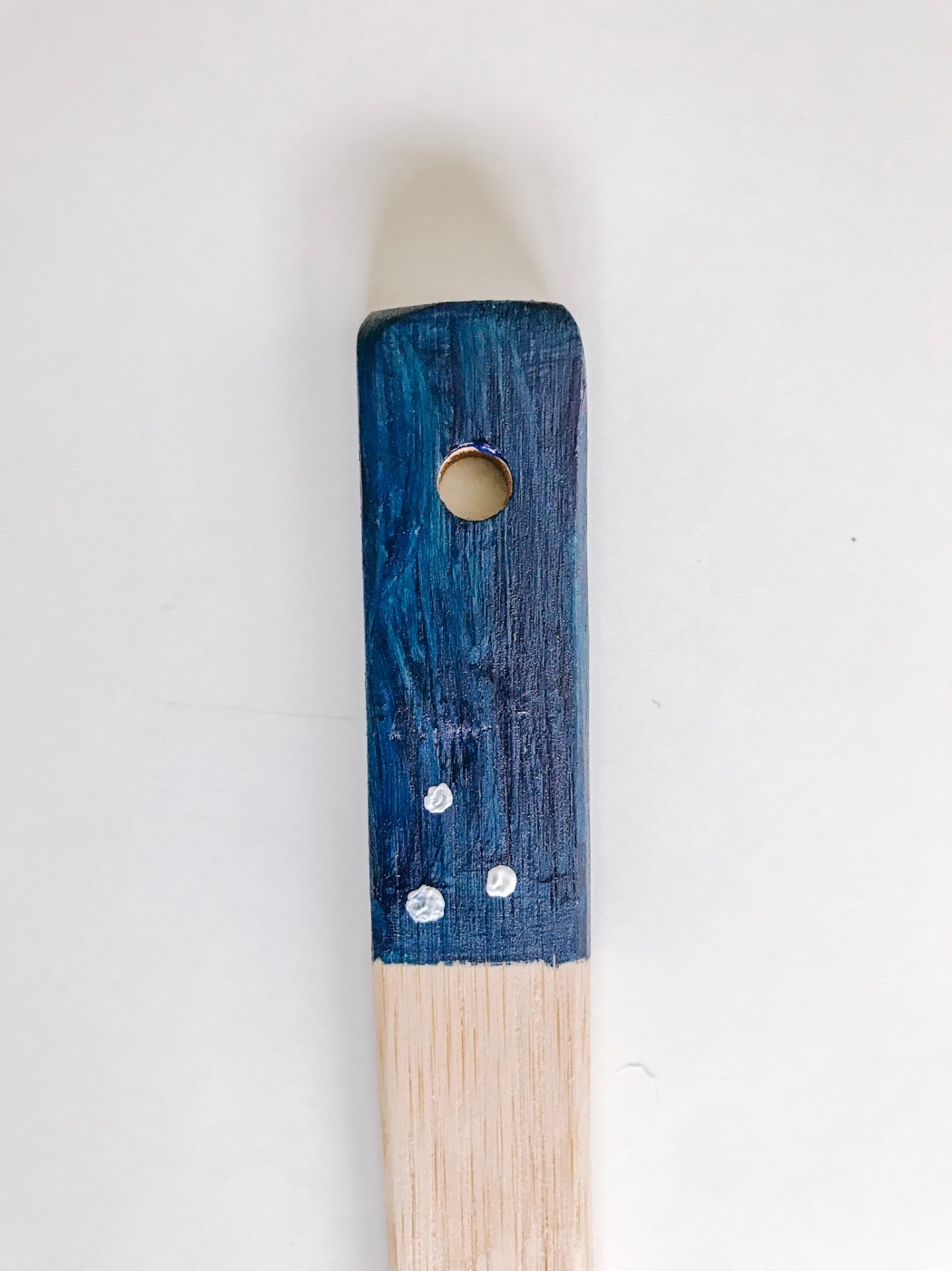 adding polka dots to the blue painted wooden spoon