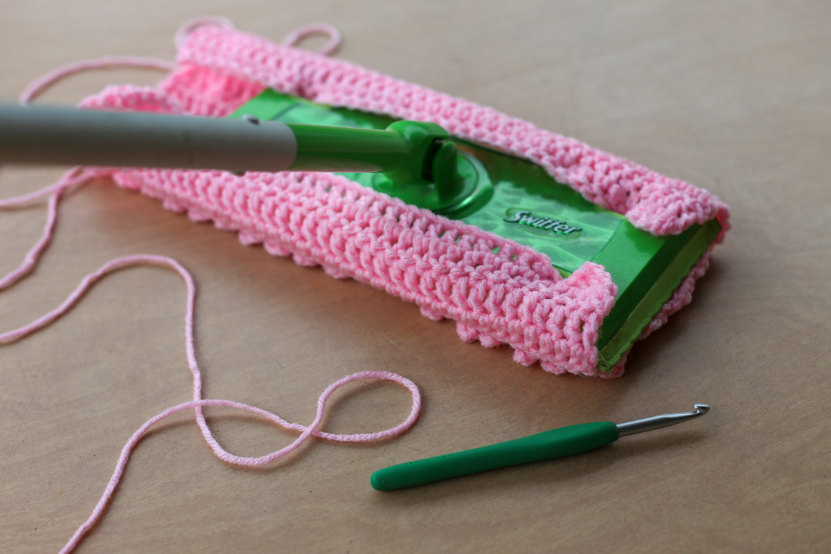 angled view of crocheted swiffer pad and swiffer and yarn