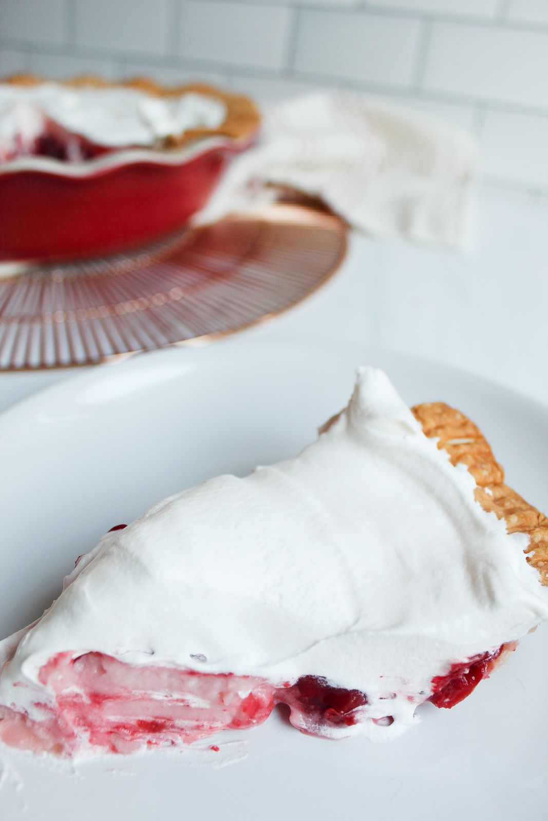 closeup pie slice with cherry cream pie in background 1