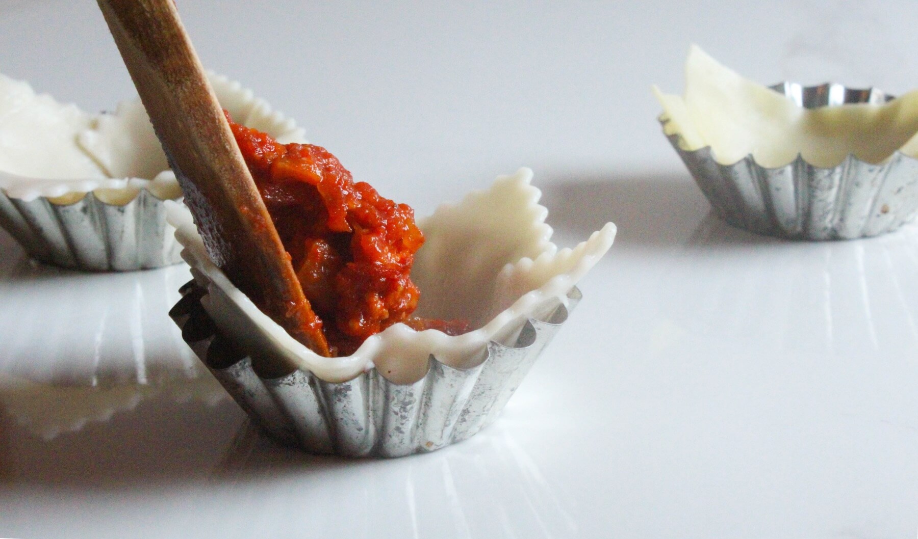 scoop tomato sauce into the lasagne cups