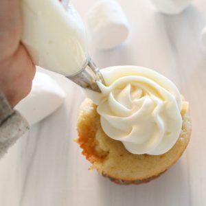 piping swirl of marshmallow icing onto cupcakes