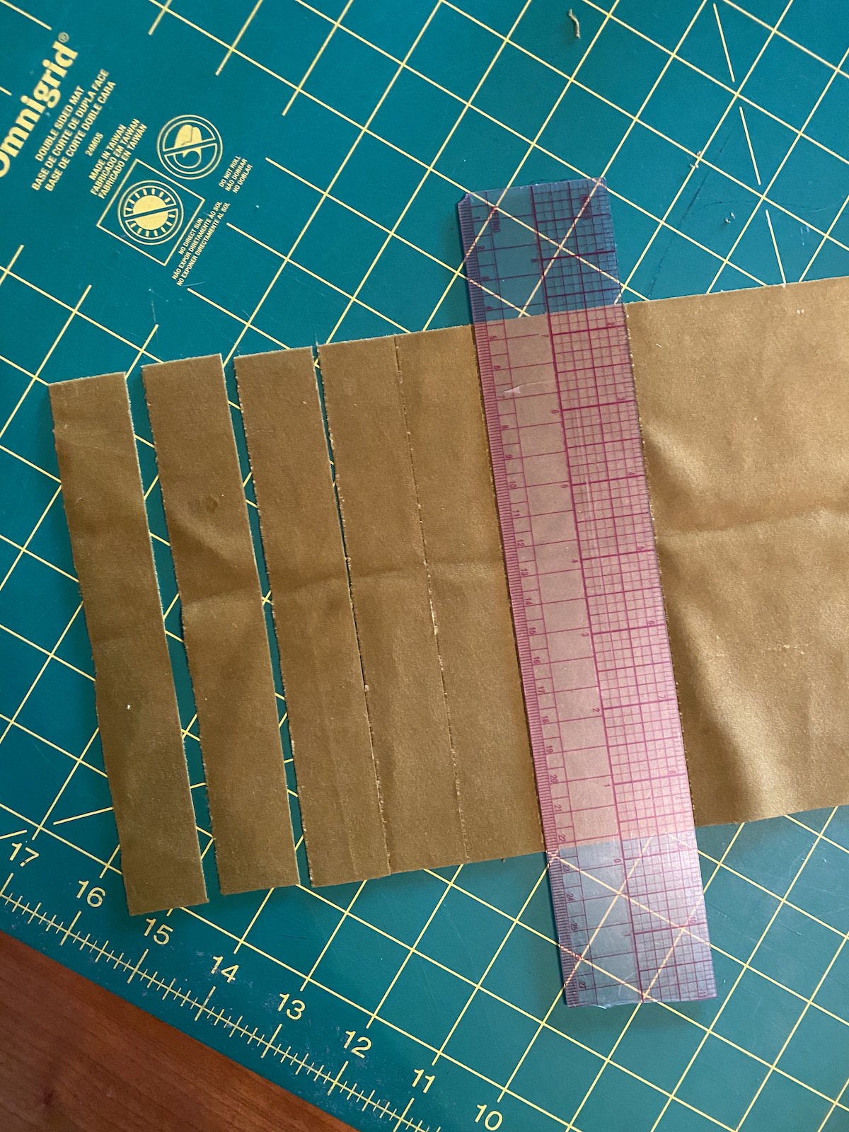 cutting out strips of velvet with a quilting ruler on a green cutting mat 